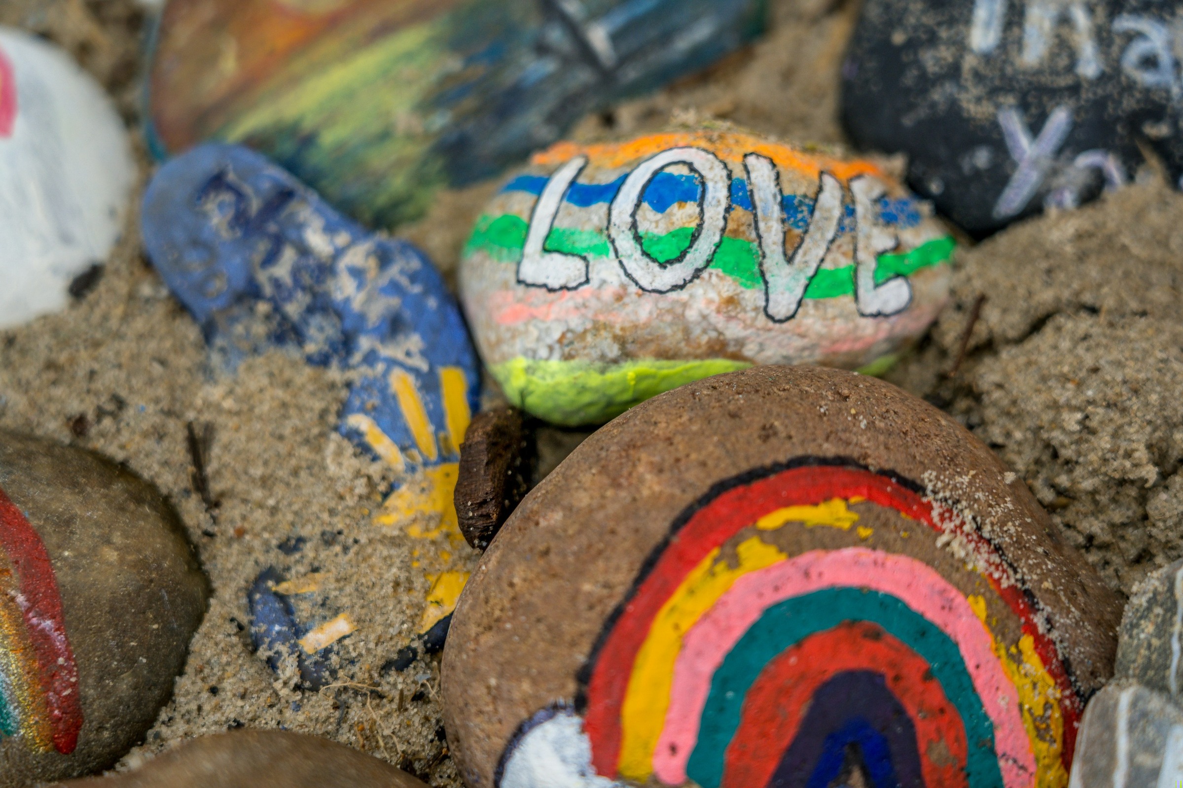 Hand-painted stones with a rainbow and the word LOVE, made at a CSN creative session